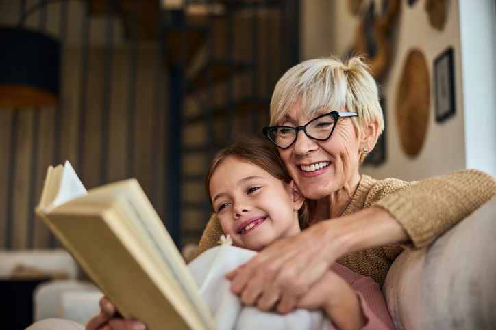 Smiling grandma and her grandchild, reading a book